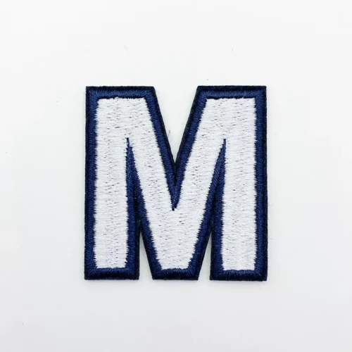 Realizzazione di toppe ricamate – Lettera “M” bianca con bordo blu